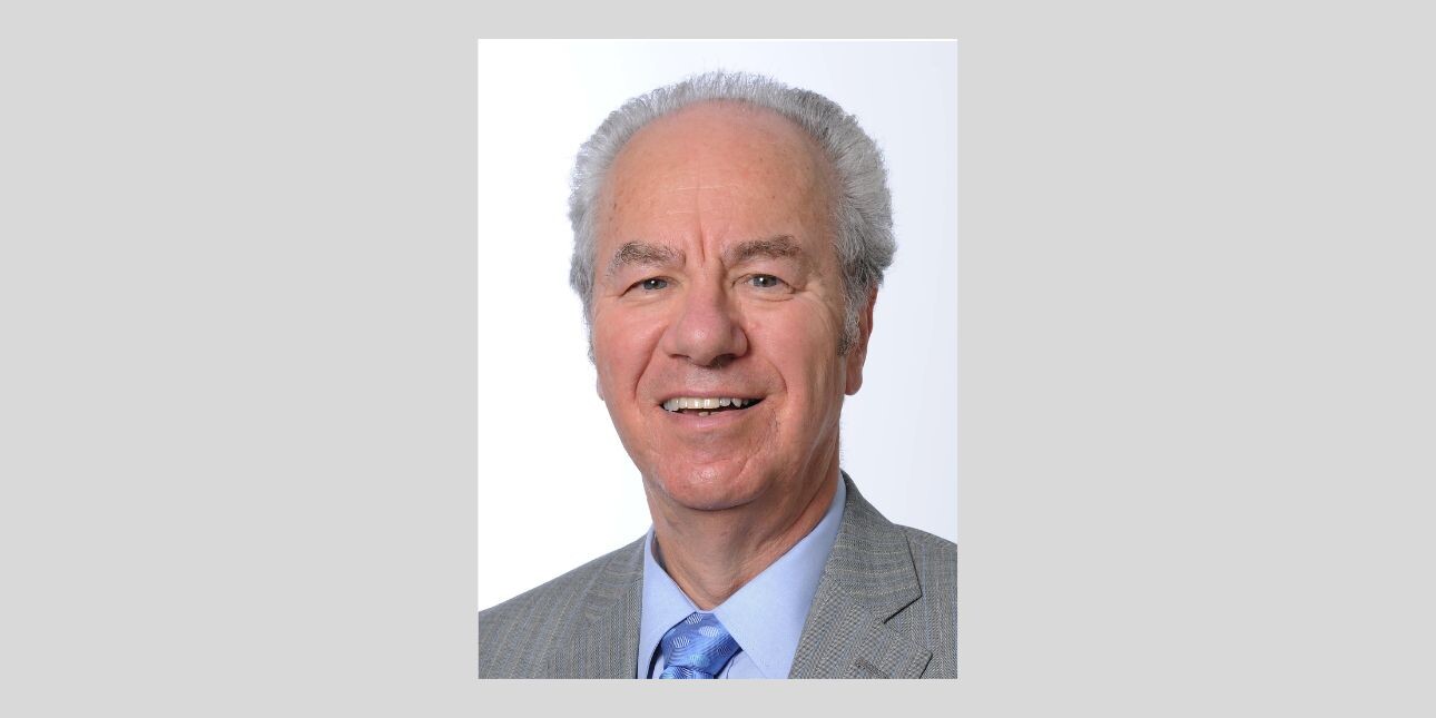 On a grey background, a colour photograph of Peter Kellner. He is a white man with grey hair, grey suit, blue shirt and blue tie.