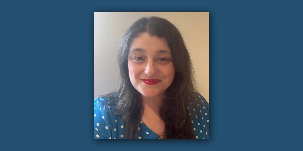 Portrait of Rachel Barker, a woman with long dark hair, red lipstick and wearing a blue blouse