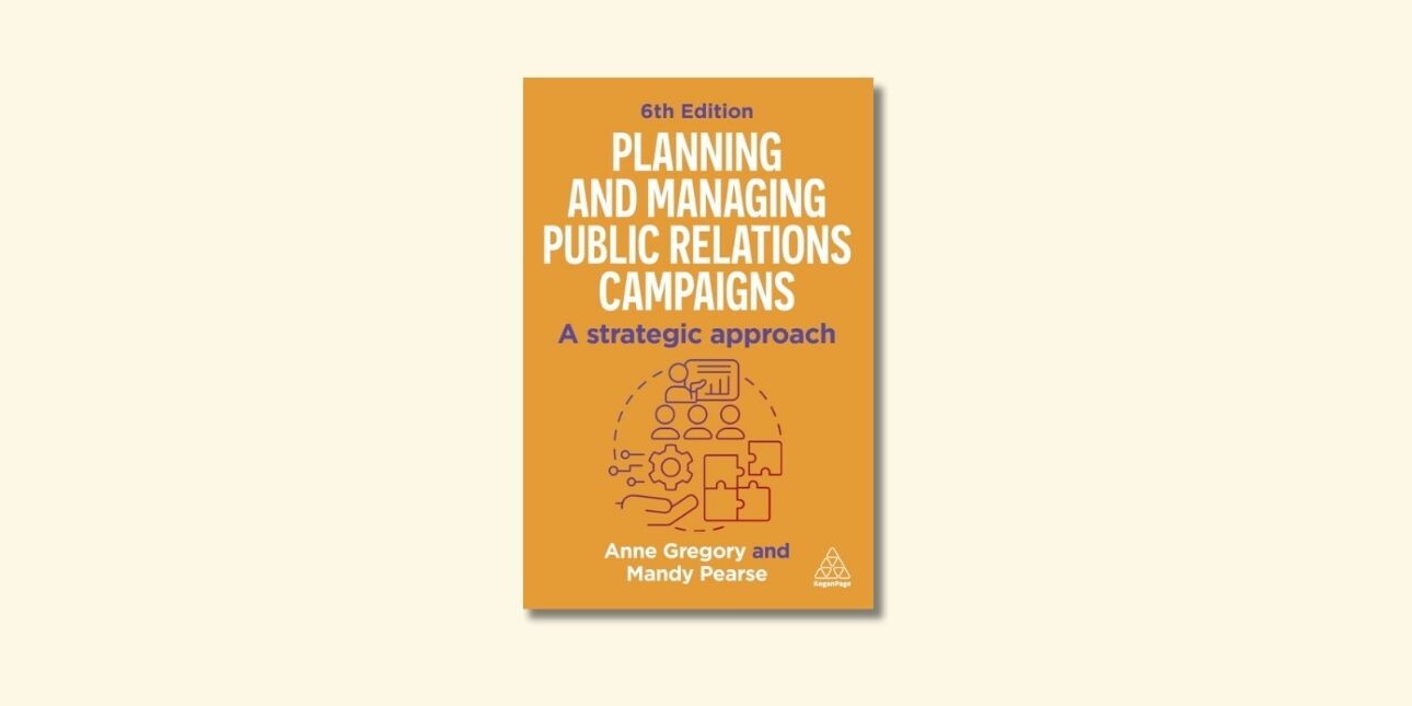 Front cover of book with yellow background, white and purple writing and a small illustration in the middle of people, puzzle pieces and a cog