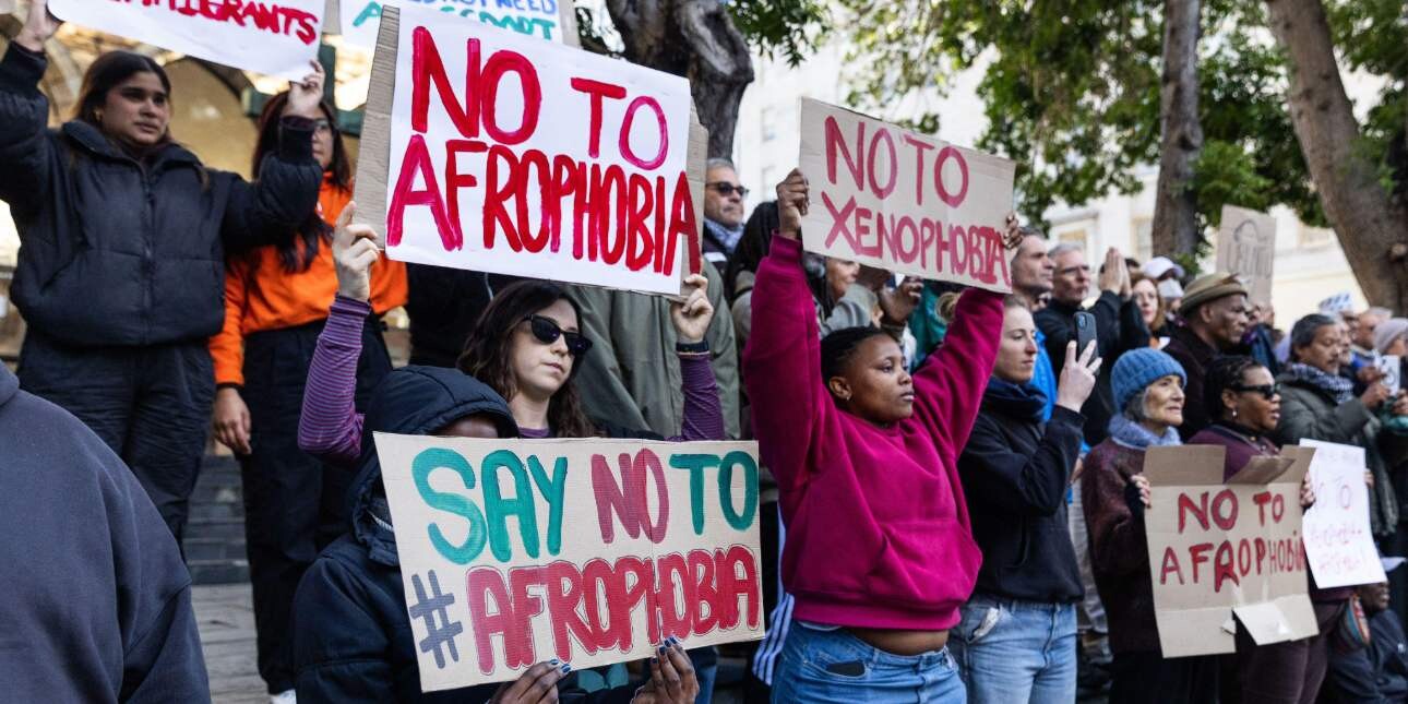 Activists hold up signs with messages urging against Afrophobia and xenophobia.