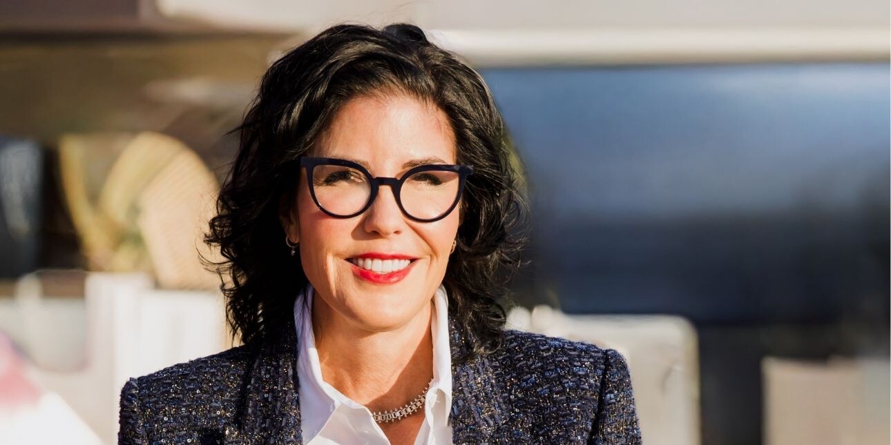 A colour photograph of Tina Fordham, who is a white woman with dark hair and glasses, wearing a grey jacket over a white shirt.