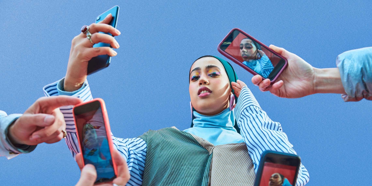 Young woman having picture taken by multiple smartphones.
