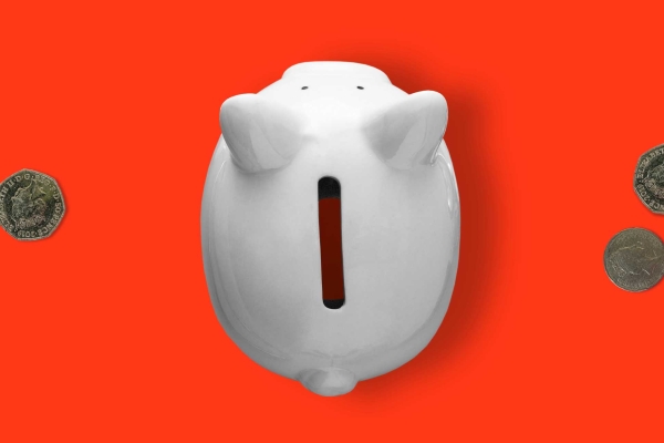 An overhead view of an empty piggy bank with three coins either side.