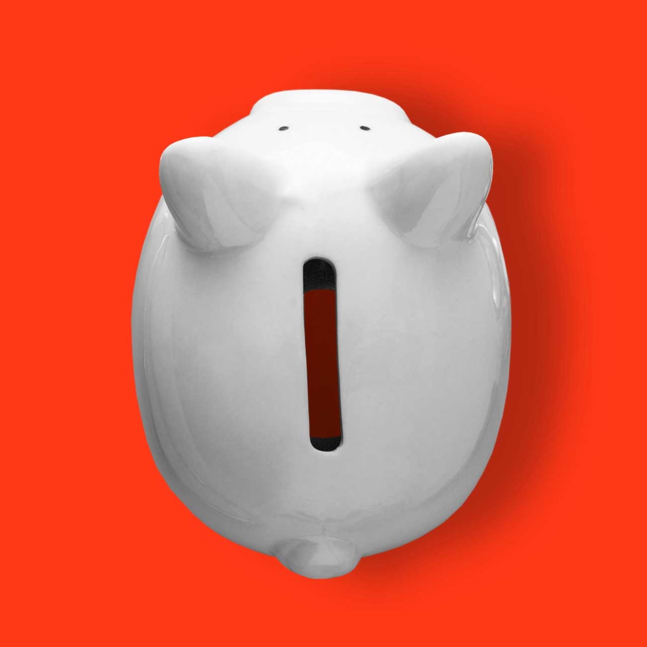 An overhead view of an empty piggy bank with three coins either side.