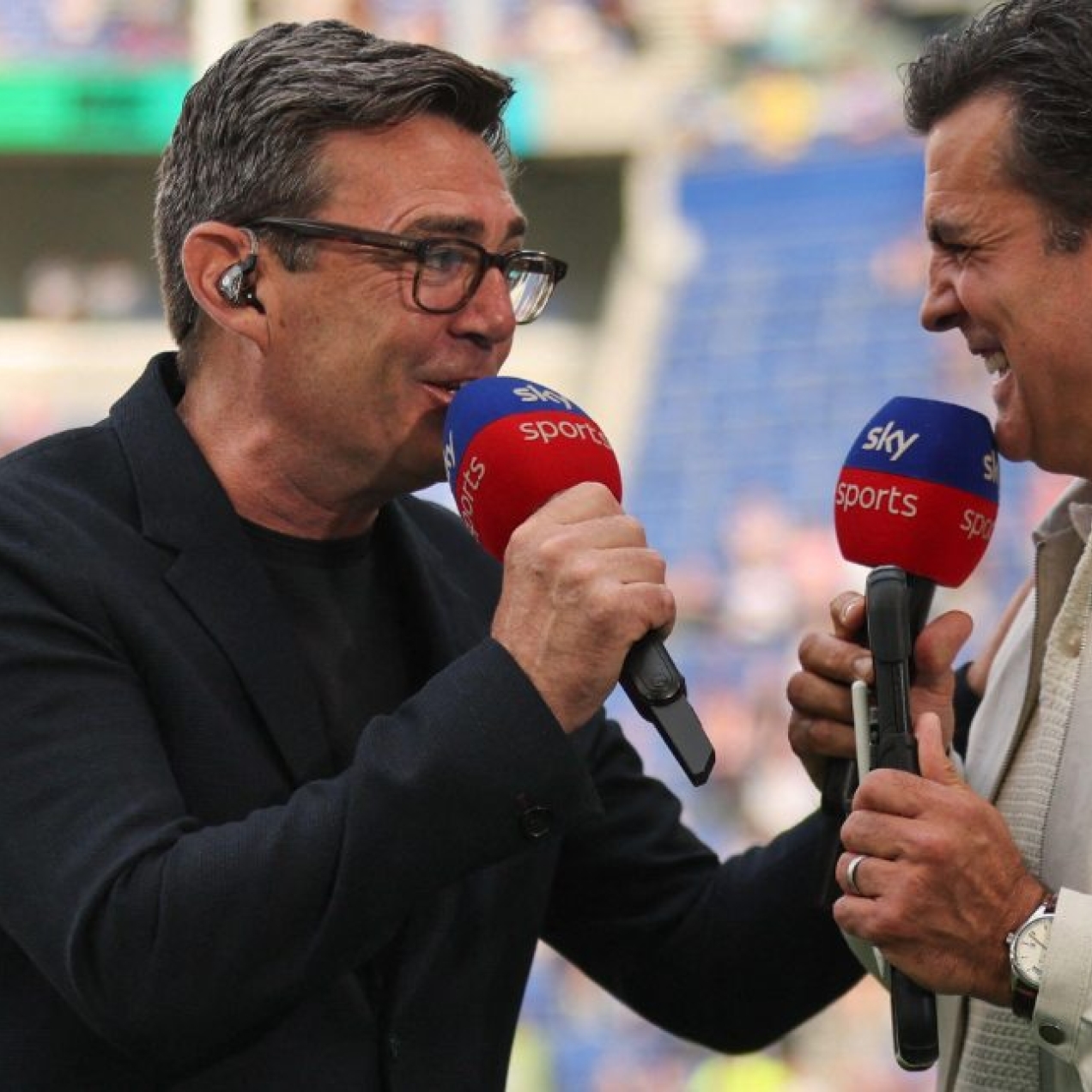 Andy Burnham in light hearted conversation with Brian Carvey on the pitch a rugby league stadium.