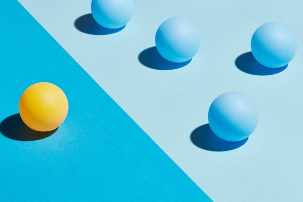 A yellow sphere sits apart from a group of blue spheres. They are divided by differently coloured areas.