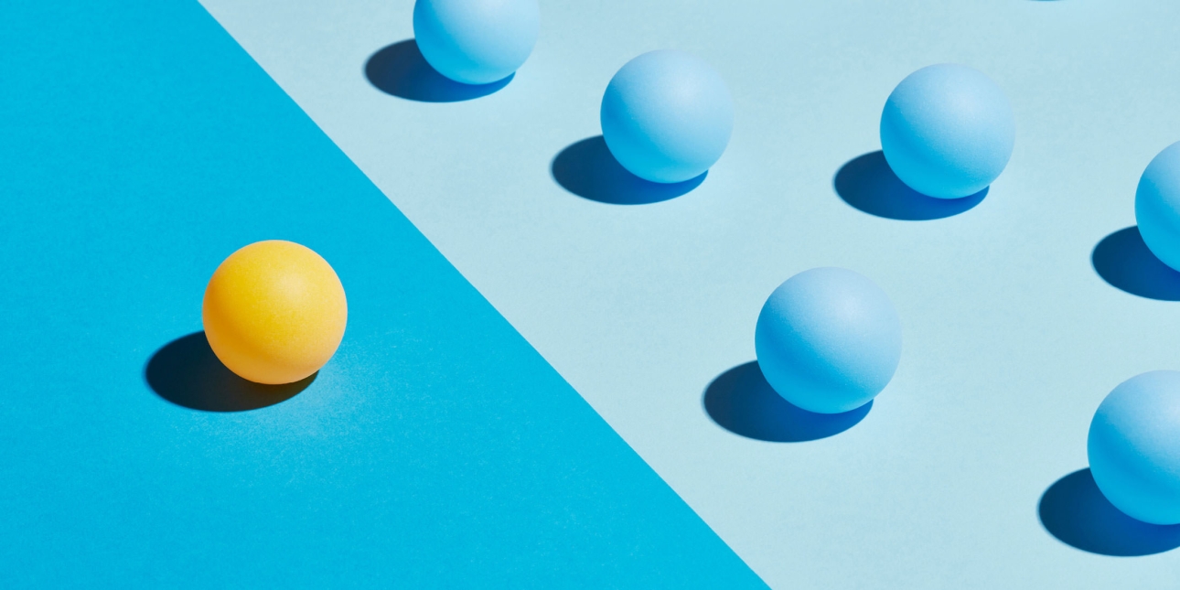 A yellow sphere sits apart from a group of blue spheres. They are divided by differently coloured areas.