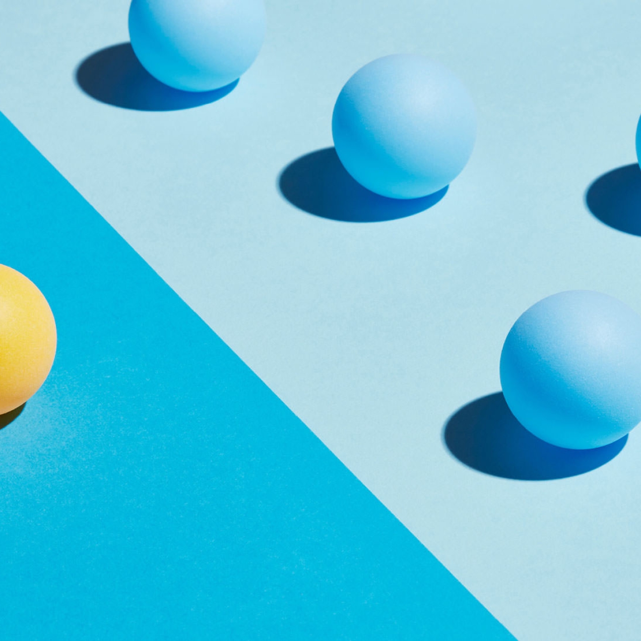 A yellow sphere sits apart from a group of blue spheres. They are divided by differently coloured areas.