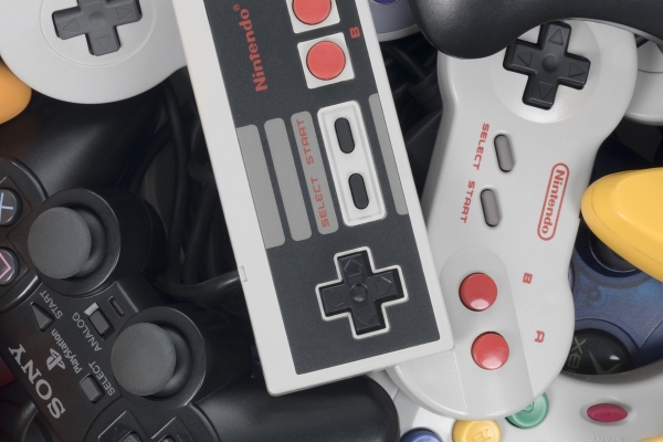 A pile of different sized, shaped and coloured hand held games consoles