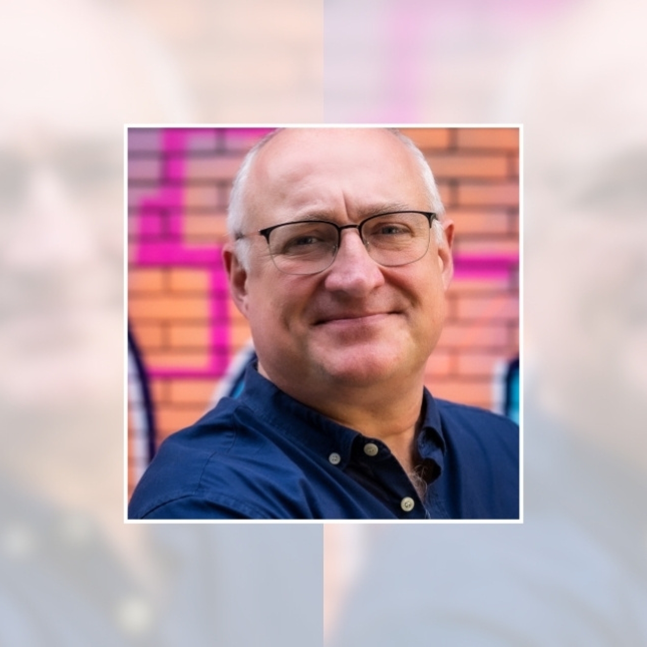 A headshot of Glenn Matchett. Glenn is white man with white receding hair, glasses and wears a dark blue shirt