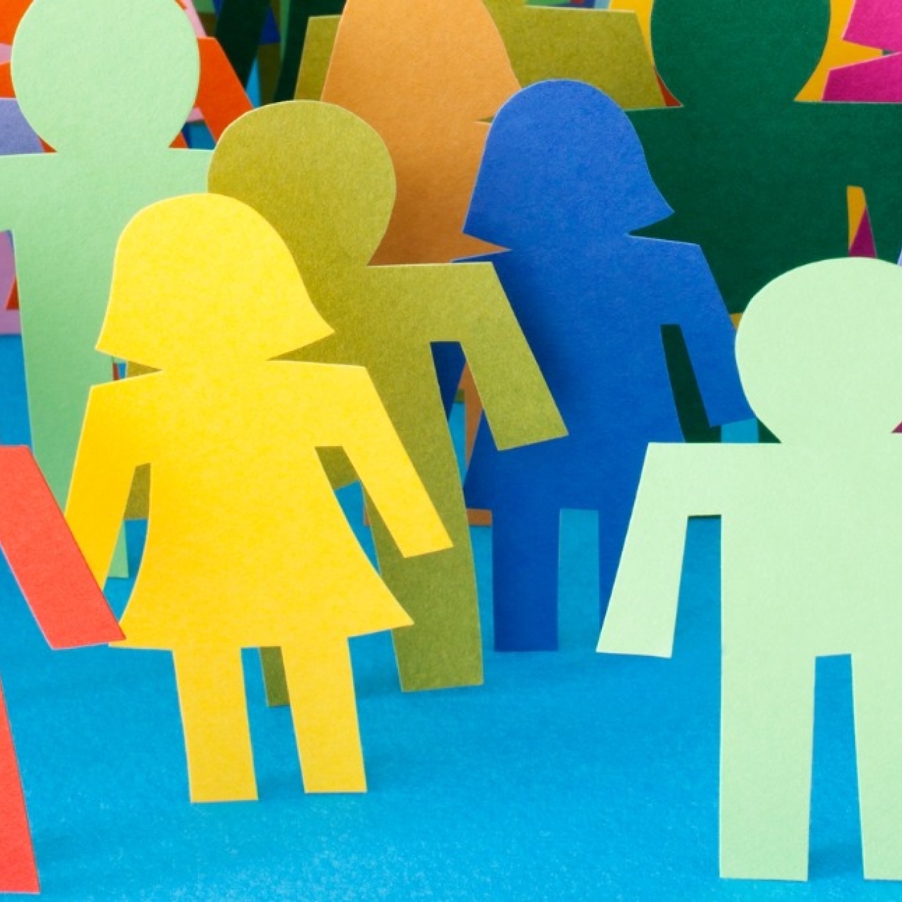 A selection of paper figures in a spectrum of colours on a blue background