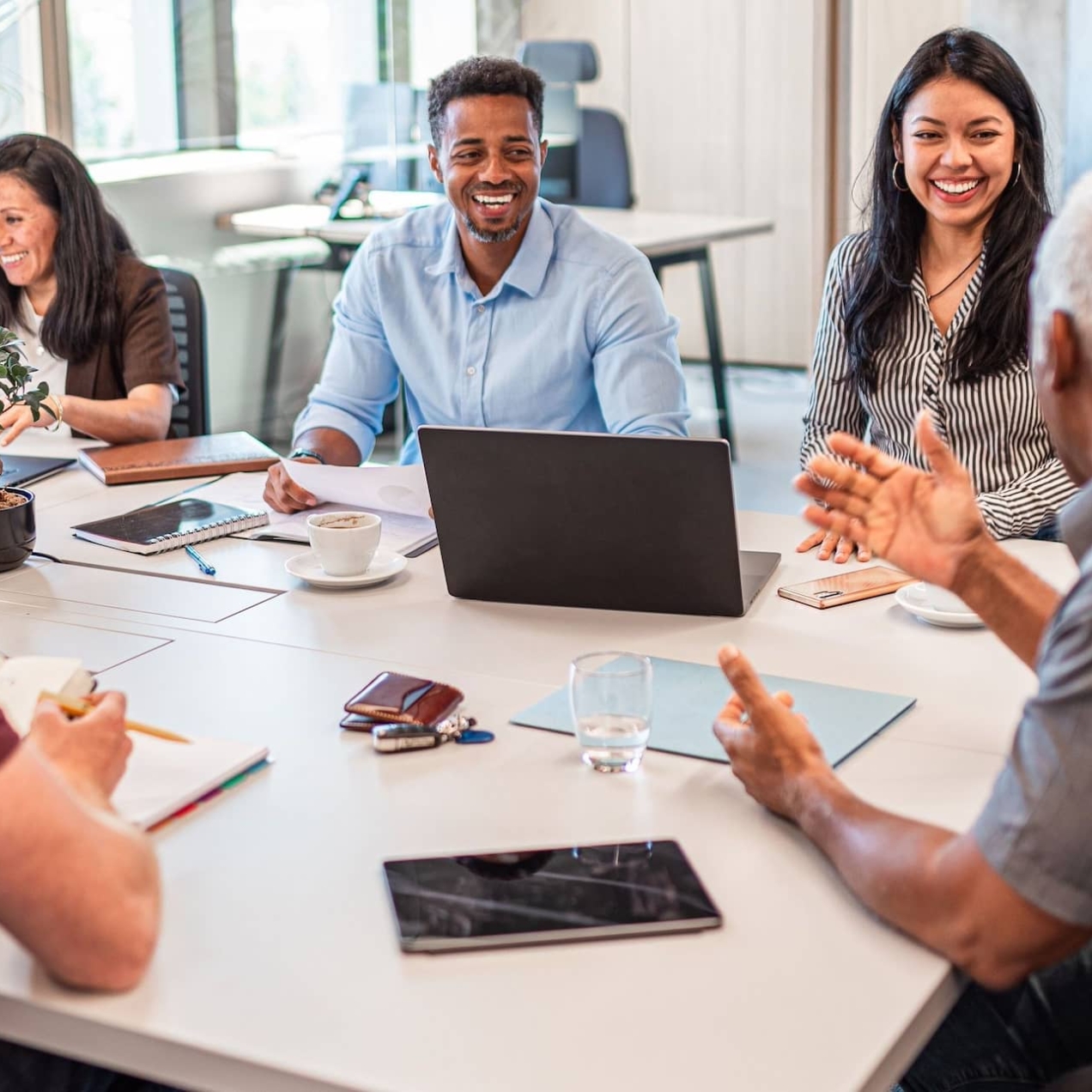 A group of five colleagues of different genders, ages and ethnicities chat around a table: