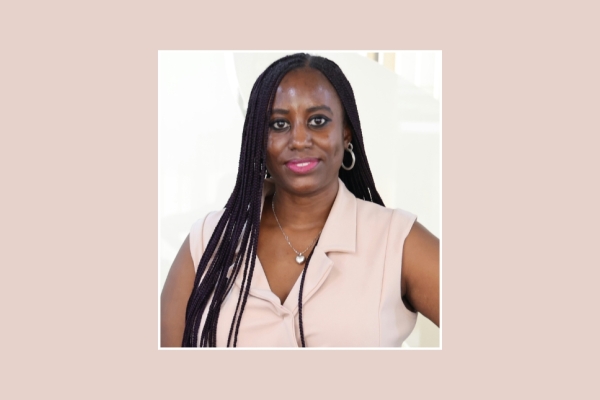 A square colour portrait of Linda Nabirye at the centre of a pastel pink background. Linda is a Black woman with long hair who wears a pastel pink top.