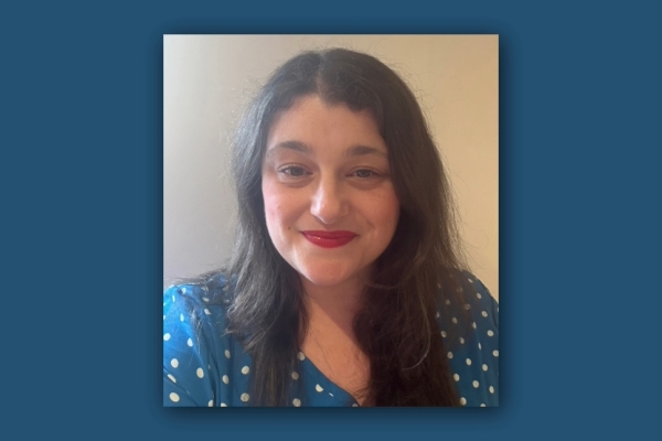 Portrait of Rachel Barker, a woman with long dark hair, red lipstick and wearing a blue blouse