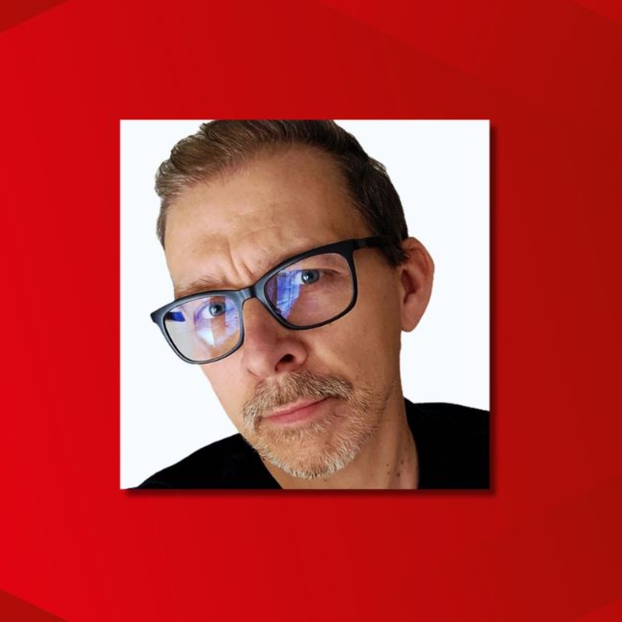 On a red background, a close up colour portrait of Rob Dyson. Rob is a white man with dark hair, glasses and shirt.