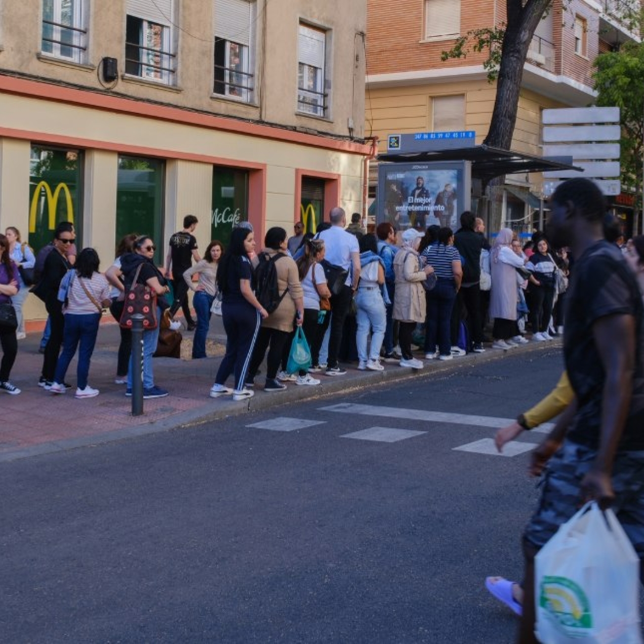 While people cross the road, others queue for a bus outside a McDonald's restaurant.