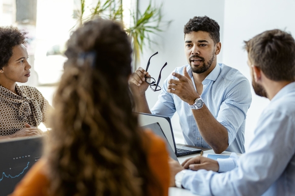 Four colleagues of different genders and ethnicities sit around a table in discussion
