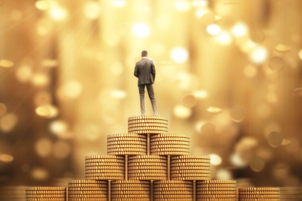 A business person stood on a stack of gold coins.