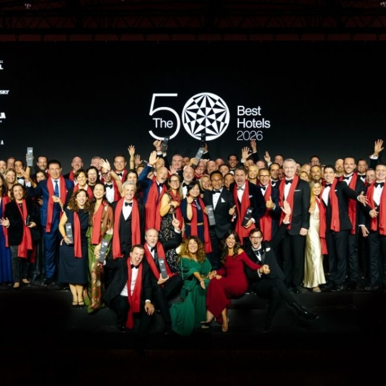 A crowd of people stood celebrating in front a banner which reads the world's best 50 hotels.