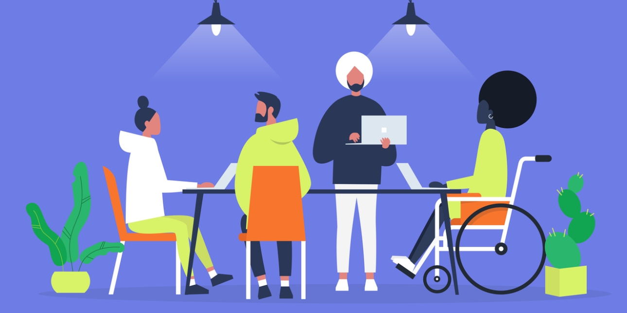 Illustration of four people at a large desk. A woman with a bun and a man with a hooded top are both sat in chairs. A man with a turban is stood holding a laptop next to a woman who is sat in a wheelchair.