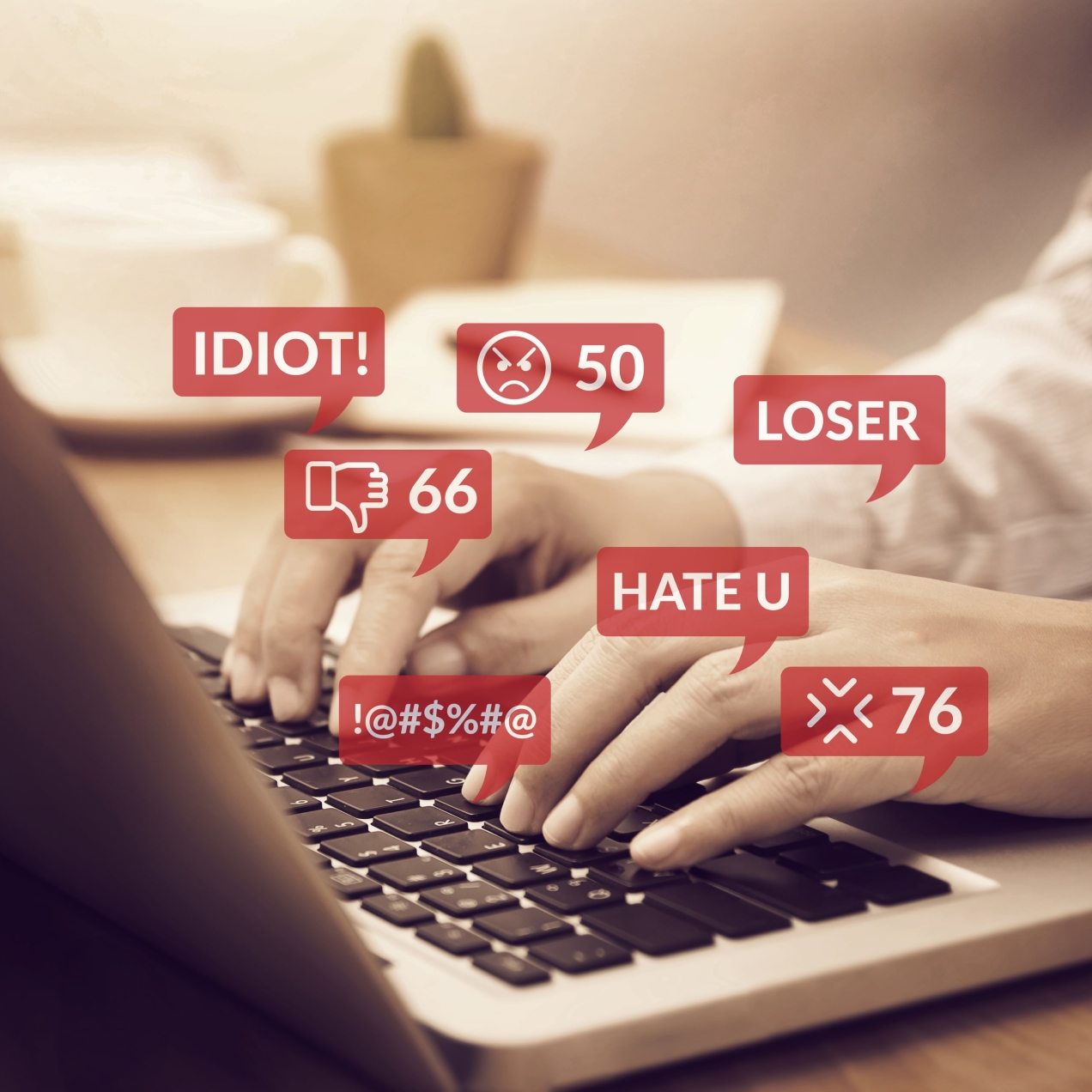 Hands typing at keyboard with speech bubbles suggesting words such as idiot, hate and loser