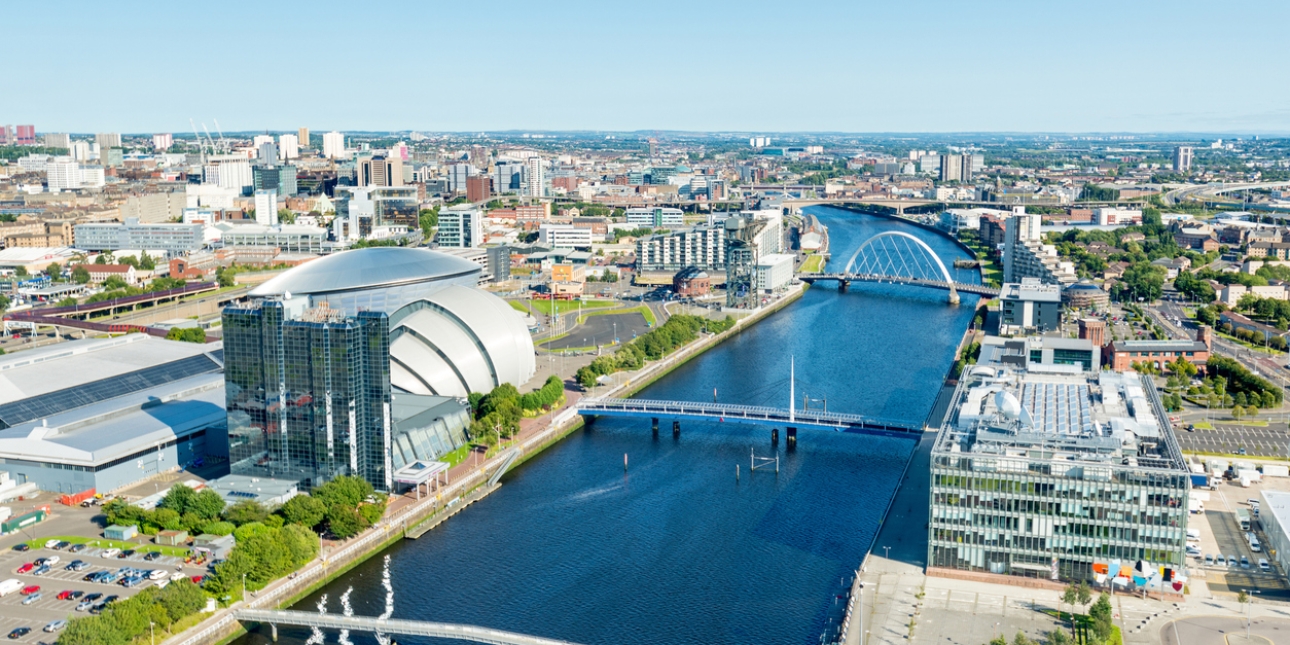 Wide angle aerial view of the River Clyde in Glasgow on a sunny day, including landmarks the SSE Hydro arena and Clyde Arc.