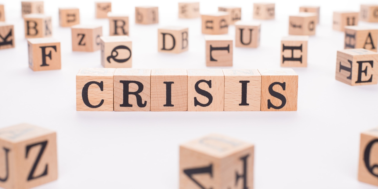The word crisis spelt out on six wooden blocks with other random letters alongside