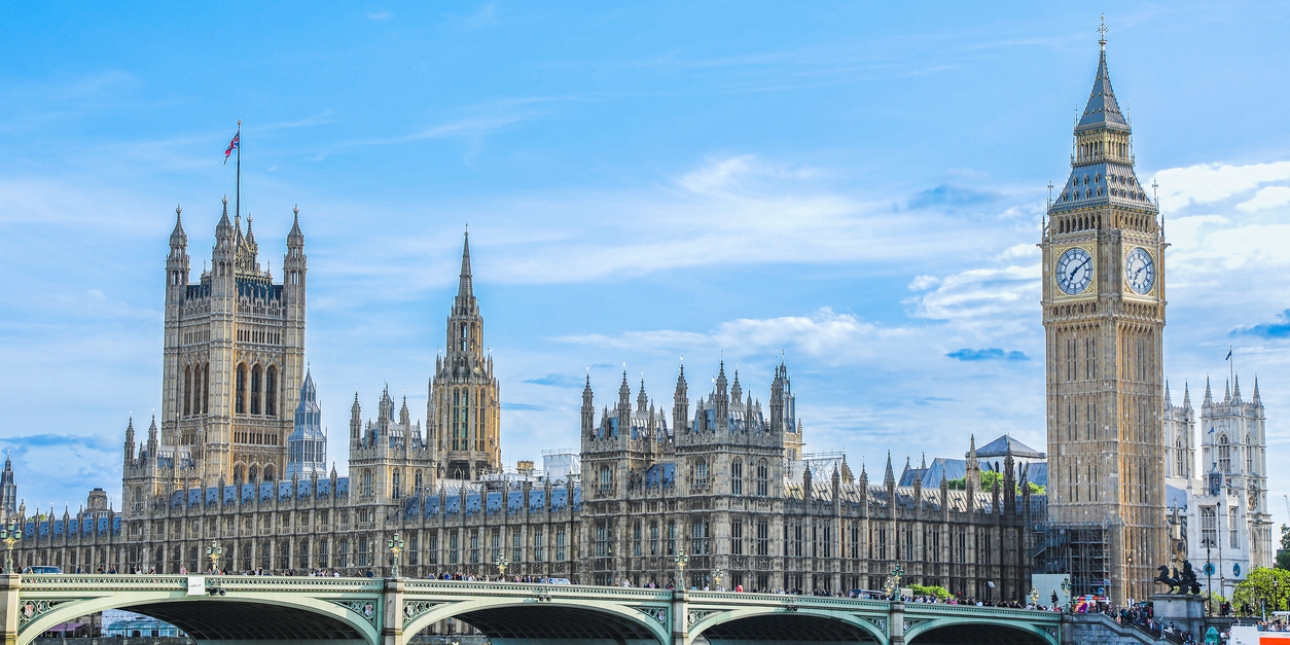 The Houses of Parliament, Westminster Bridge and Big Ben against a blue sky with few clouds and photographed from the south bank of London's River Thames