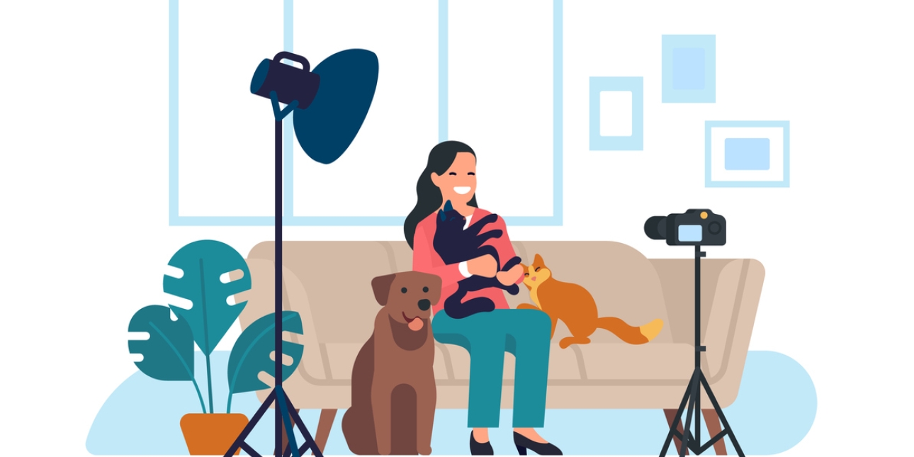 Illustration of a woman on a sofa with two cats and a dog. She is looking at a video camera on a tripod.