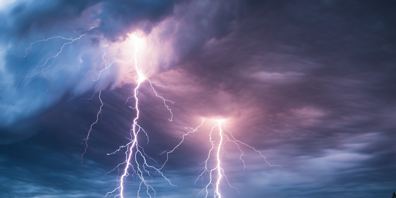 Dark thundery clouds lit up in places by several lightning bolts