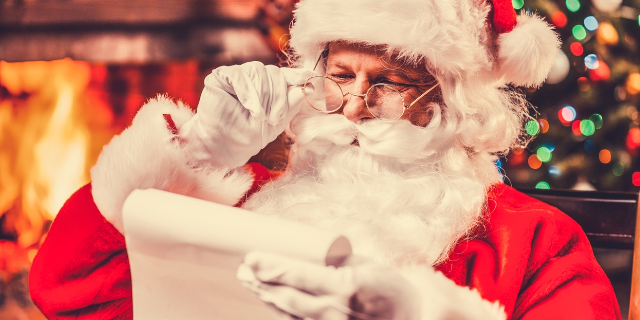 Father Christmas holding his spectacles as he reads a letter