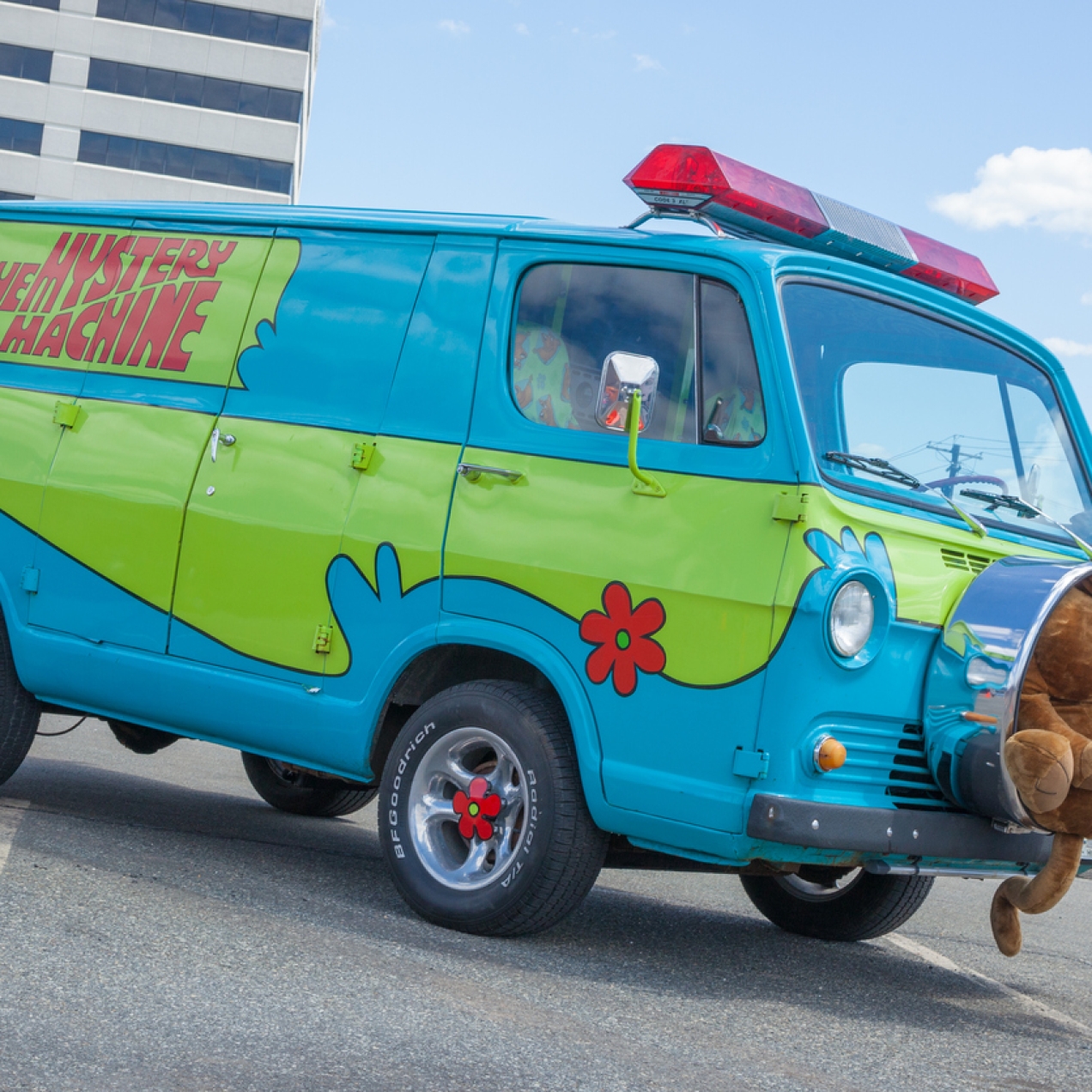 A van painted in blue and green with the words Mystery Machine on the side to emulate the van in the Scooby Doo cartoon. A soft toy Scooby Doo sits in the middle of the spare tyre at the front.