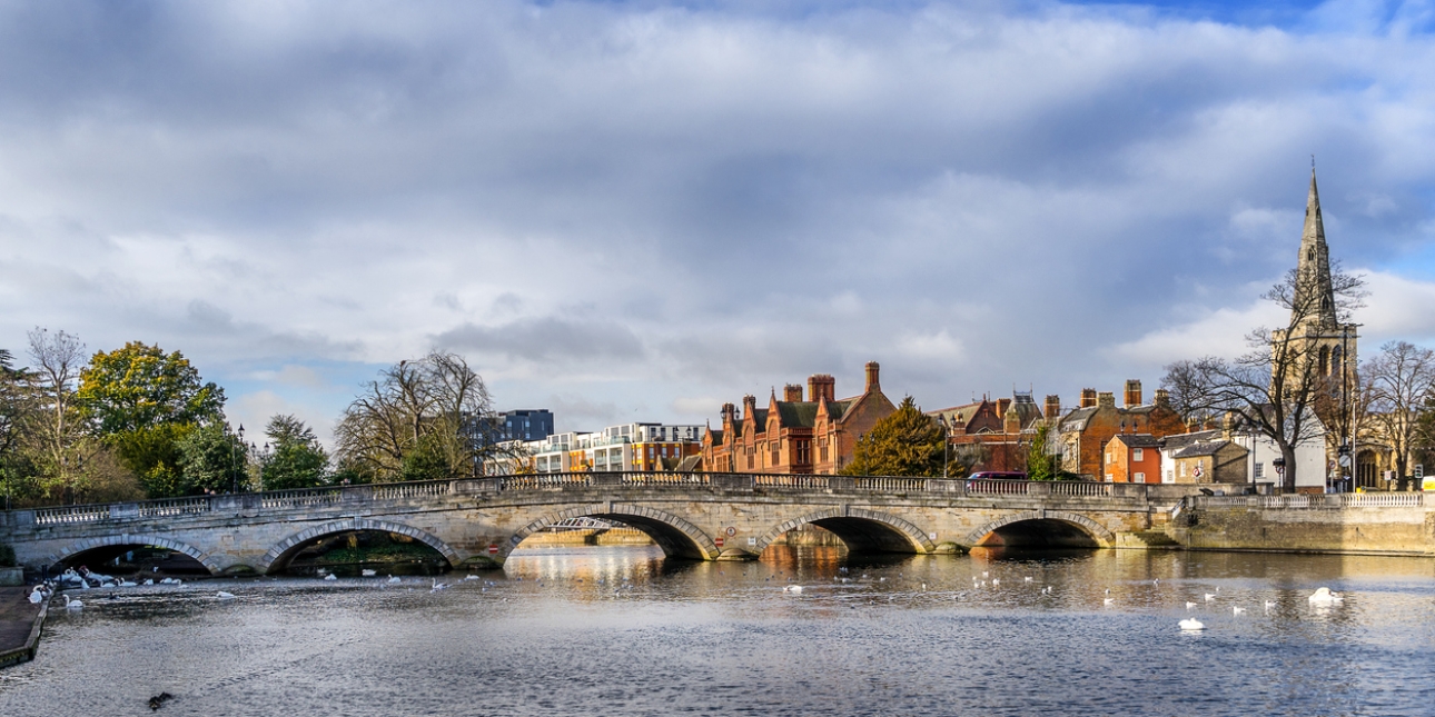Bedford bridge across the Ouse river with redbrick buildings and a church spire in the background