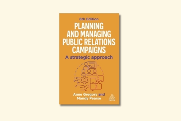 Front cover of book with yellow background, white and purple writing and a small illustration in the middle of people, puzzle pieces and a cog