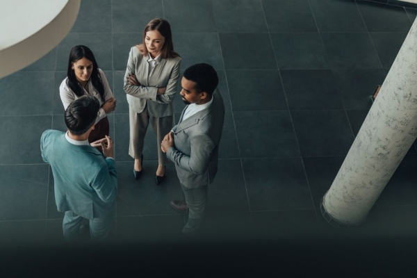 An overhead shot of four professional business people stood in discussion in a modern office.
