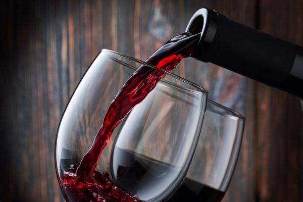 Red wine being poured from a bottle into two glasses.