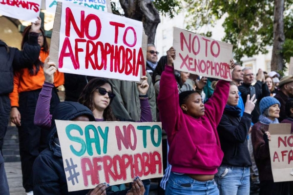 Activists hold up signs with messages urging against Afrophobia and xenophobia.