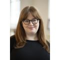 Portrait of Orla Graham, a white woman with long brown hair wearing dark rimmed glasses and a black top