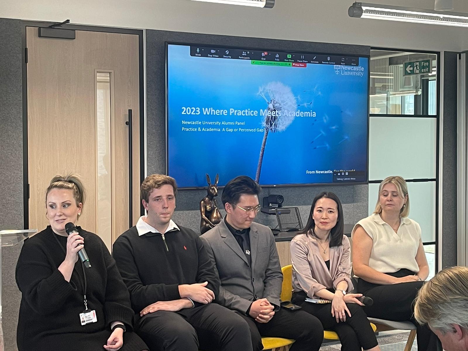 Five members of Newcastle University's alumni panel sat on chairs in front of the audience and behind a large screen showing the event title