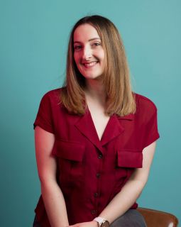 Amy Stone smiling at the camera against a turquoise background