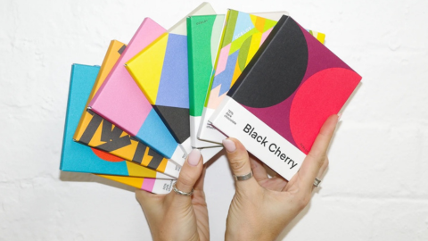 Two hands holding up a range of brightly coloured Ocelot chocolate bars