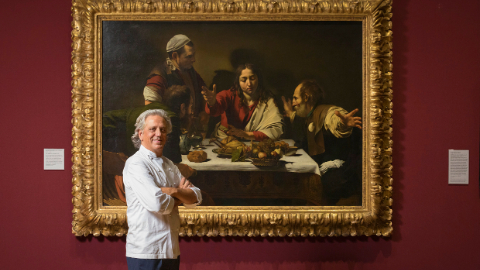 Chef Giorgio Locatelli stood in front of a gold framed painting of The Supper which is hung on a burgundy wall