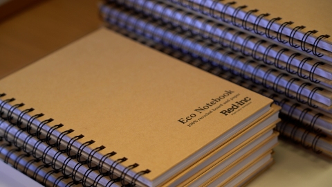A pile of bound notebooks with light brown covers and the words Red Inc eco notebook written on them.