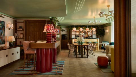 A co-working space with pink pastel stools are around a plinth, tables and chairs, pistachio ceiling and assorted lighting,