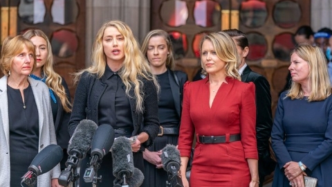Amber Heard in front of six microphones flanked by six colleagues.