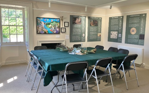 A conference room with poster on the walls and a table with chairs around it in the centre