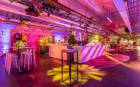 Tables and stalls along with a bar underneath pink and yellow lights